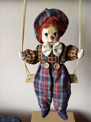 Marioneta klovn sa mašnom na ljuljašci sa kanapom